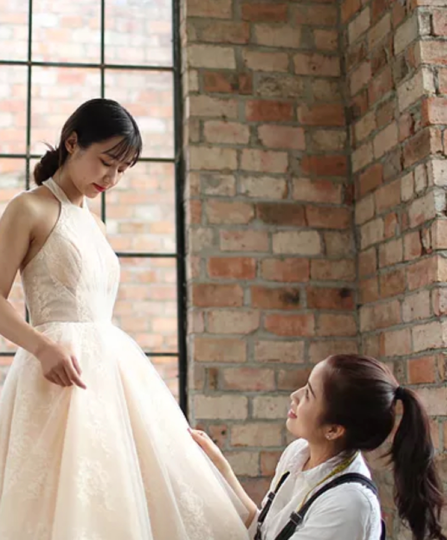Seamstress offering alteration services to a bride in a wedding dress